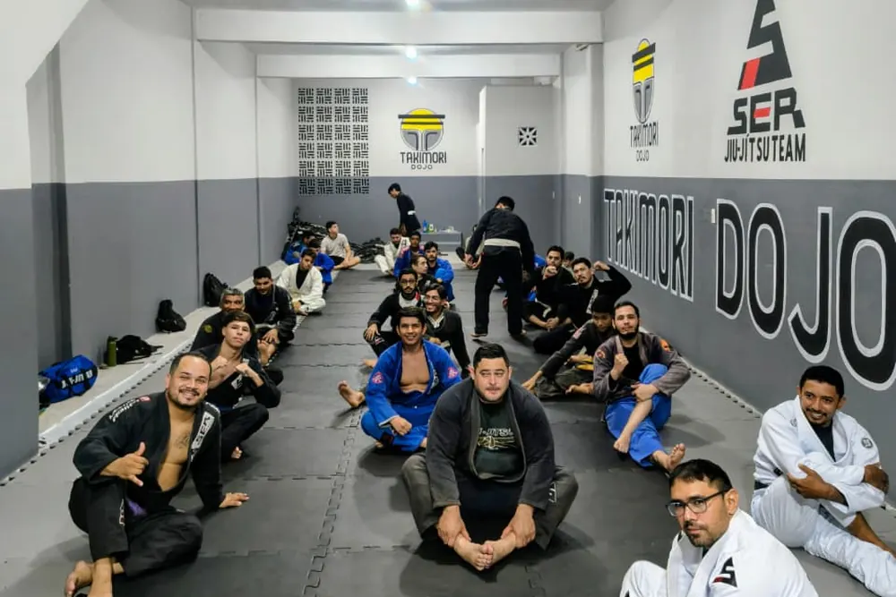 Turma reunida no tatame ao lado do professor